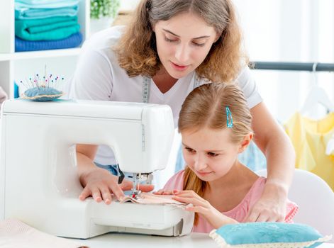 Little girl is taught to sew