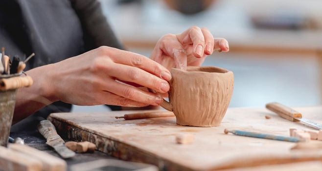 Hands of potter forming cup from clay