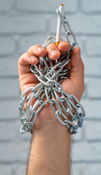 Male hand in metal chains holding cigarette