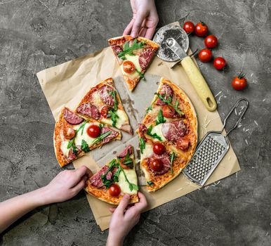 children's hands take homemade pizza with salami