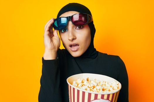 cheerful woman in black hijab popcorn 3D glasses cinema ethnicity model. High quality photo