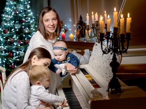 Two mothers with children in the New Year at a white grand piano