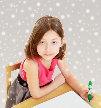 Little girl draws felt-tip pen on a white surface.
