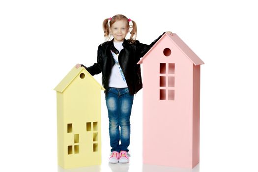Little girl is playing with wooden houses.