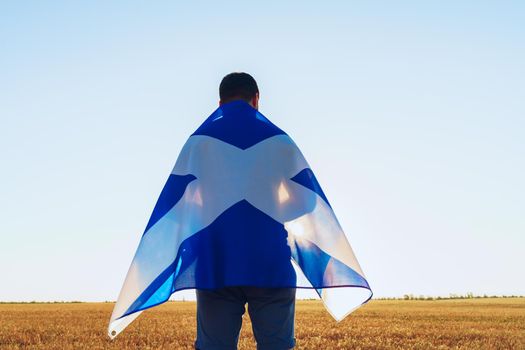 Man with a flag of Scotland standing in field