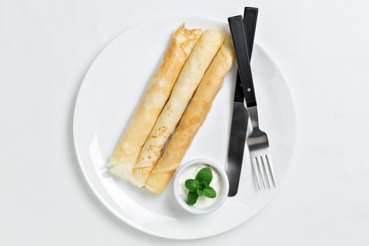 Russian pancakes served in rolls with sour cream