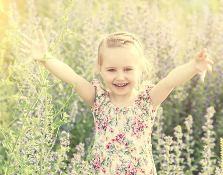 child in field among flowers and herbs, smiling