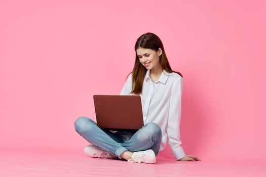 woman sitting on floor with laptop online shopping shopping technology pink background. High quality photo