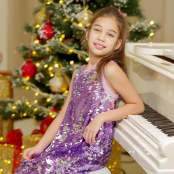 Little girl near the piano and Christmas tree.