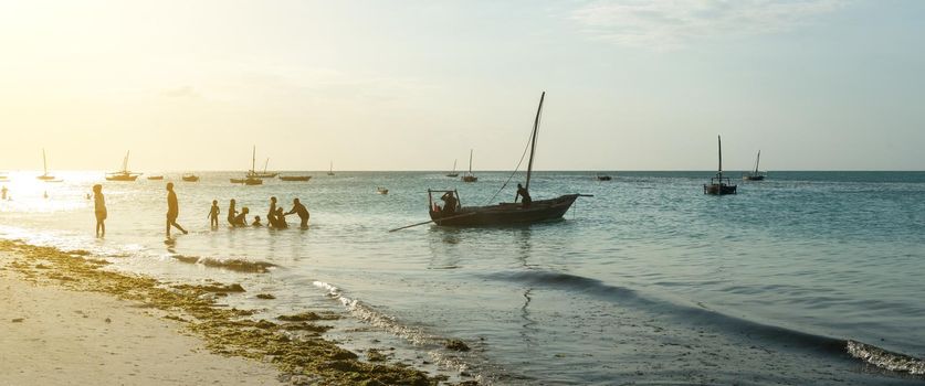 people and wooden fishing ship in water near fishing village in Zanzibar