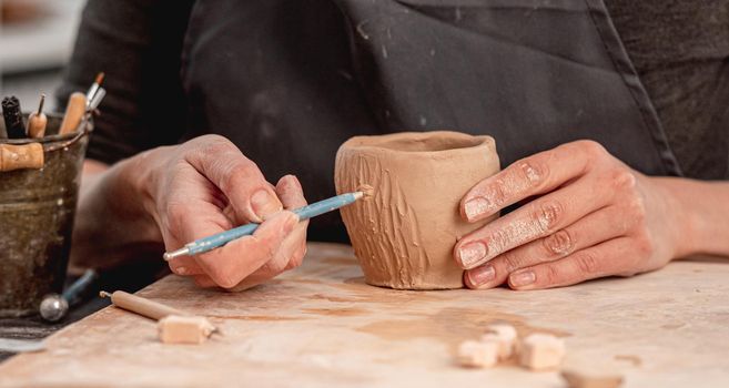 Potter using carving tool on mug