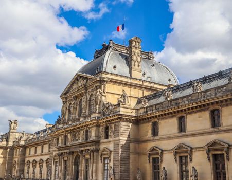 Paris / France - April 04 2019: Architectural details of the facade of the Louvre in Paris with the French flag on the roof