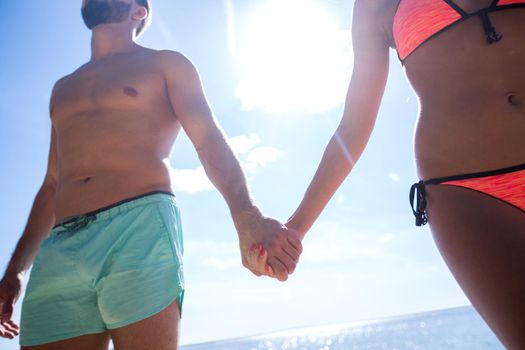 Couple on the Beach in Swimwear Holding Hands