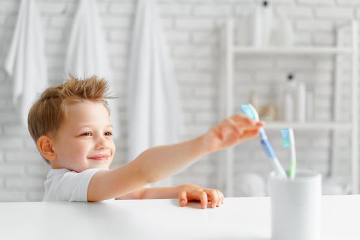 Little boy reaching out for toothbrush in bathroom