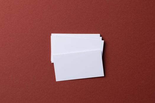 Blank white business cards on burgundy paper background