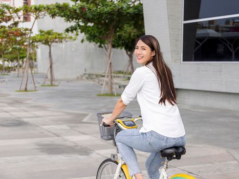 Young attractive woman riding a bicycle through the city park