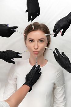 Conceptual beauty and cosmetology image of hands of several doctors holding syringes. Beauty and Cosmetology concept. Cosmetic procedures mesotherapy