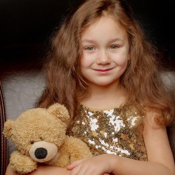 Little girl with a teddy bear on a black background.