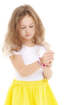 A little girl puts a bracelet on her arm.