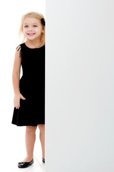 A little girl is looking from behind an empty banner.
