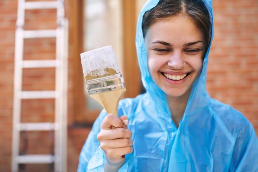 cheerful woman house painter in protective suit repairing home