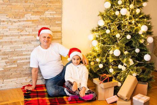 Little girl with grandfather sitting on floor a during Christmas, Little girl and grand parents in living room during christmas.