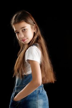 Little girl in denim clothes on a black background.