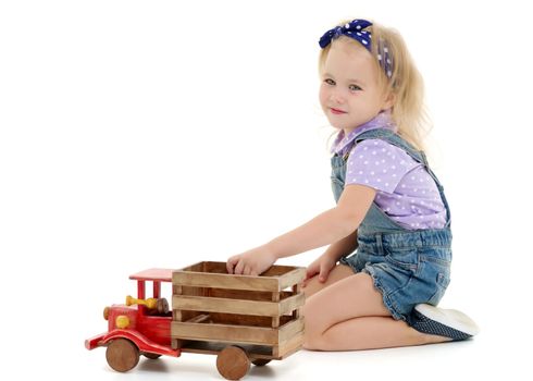 Little girl is playing with a wooden car.