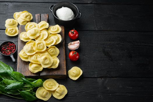 Raw ravioli with ricotta and spinach, on wooden cutting board, on black wooden table background, with copy space for text