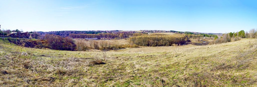Panorama. A hilly landscape in early spring, when the grass is just beginning to turn green. Spring Russian landscape, Moscow region, Russia.