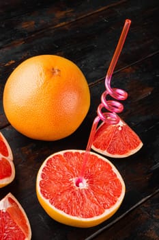 Whole and sliced grapefruits , on old dark wooden table background