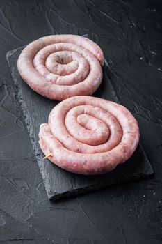 Traditional raw spiral pork sausages, on black background