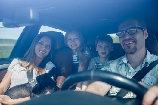 family with two children traveling in a family car