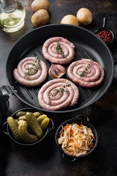 Sauerkraut with grilled sausages in cast iron frying pan, on old dark rustic background