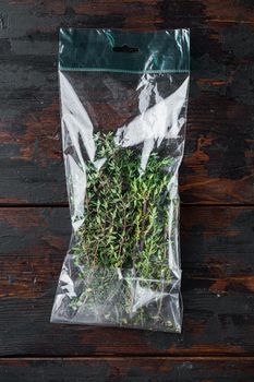 Thyme in plastic bag, on dark wooden background, top view flat lay