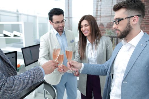business team raises glasses of champagne in the office
