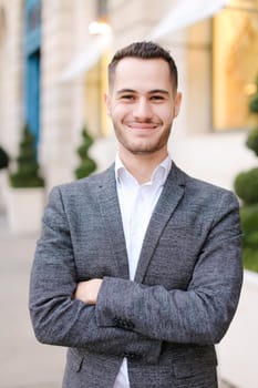 Portrait of happy young caucasian man wearing grey suit outdoors.