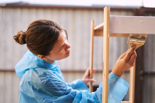 woman house painter renovating wood fittings at home