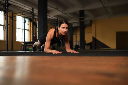 Portrait of a muscular woman on a plank position.