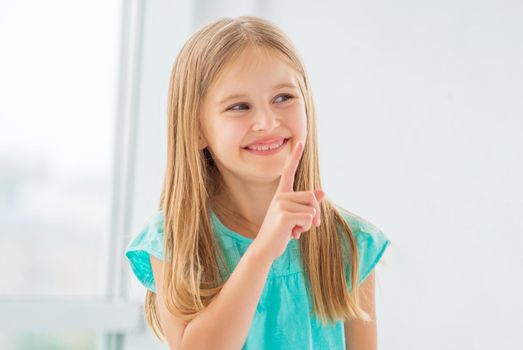 Little girl with pretty smile showing index finger