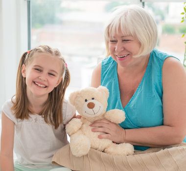 Grandmother and granddaughter playing with plush teddy