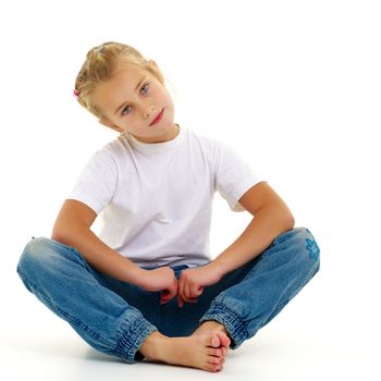 A little girl is sitting on the floor in a clean white T-shirt.