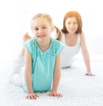 Girl doing physical exercises with mother