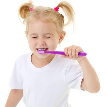 A little girl brushes her teeth.