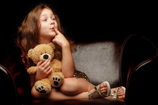 Little girl with a teddy bear on a black background.