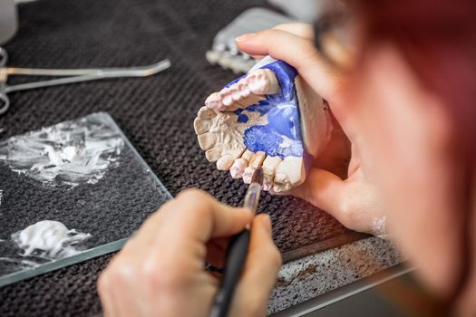 Dental technician is painting a tooth model