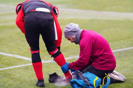Sports doctor using freezing spray while treating injured sportman