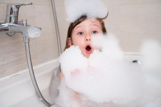 little girl in bath playing with foam