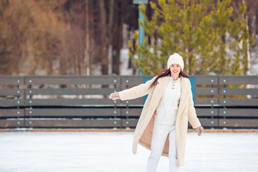 Smiling young girl skating on ice rink outdoors