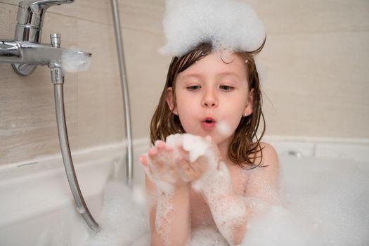 little girl in bath playing with foam